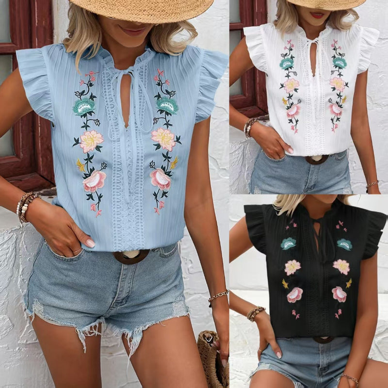 Close-up of a white sweetheart flutter sleeve embroidered blouse with delicate floral patterns.