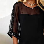 Black sheer sleeve top with sequin details on a plain background
