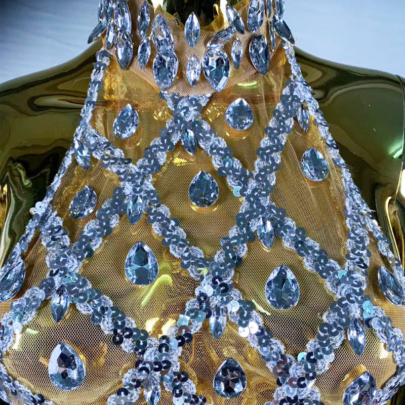 Close-up of a decorative headpiece with blue gemstones on a gold background