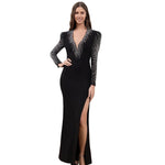 A model wearing a solid black deep V-neck high slit maxi dress with a halter neck.