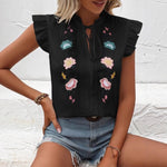 Close-up of a white sweetheart flutter sleeve embroidered blouse with delicate floral patterns.