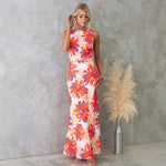 Woman modeling a one-shoulder printed sleeveless backless midi dress in lake blue, standing at sunset
