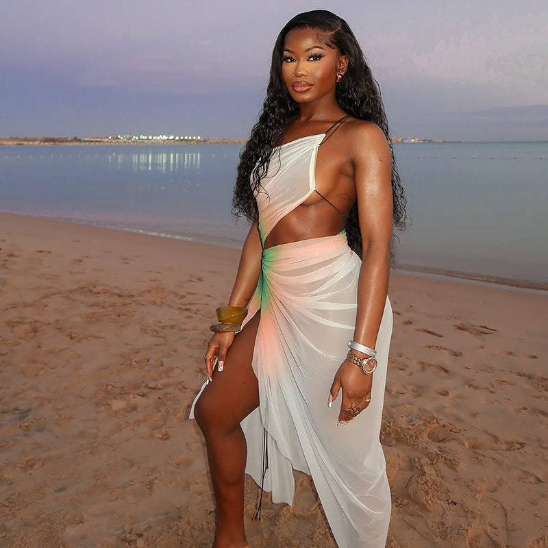 A woman wearing a white, sheer mesh midi dress with a high slit and a stylish oblique neckline. The dress is sleeveless and fitted.