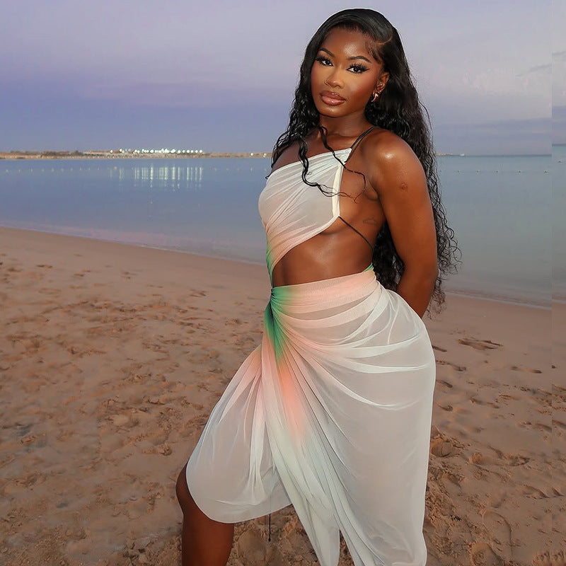 A woman wearing a white, sheer mesh midi dress with a high slit and a stylish oblique neckline. The dress is sleeveless and fitted.