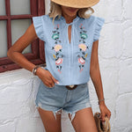 Close-up of a white sweetheart flutter sleeve embroidered blouse with delicate floral patterns.