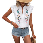 Close-up of a white sweetheart flutter sleeve embroidered blouse with delicate floral patterns.