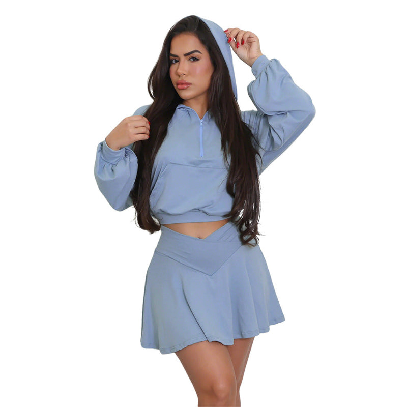 A model wearing a solid color two-piece outfit consisting of a short skirt, long pants, and a hoodie top.