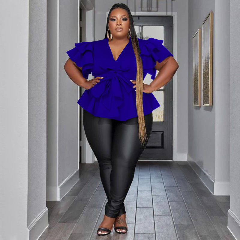 Woman wearing a blue top and black pants in a hallway