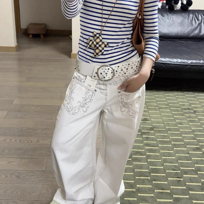 A pair of white, retro-style curved knife jeans with reverse embroidered detailing. The unique seam and leg shape are visible, highlighting the modern and edgy design.
