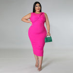 Woman wearing a bright pink dress holding a green clutch against a gray background