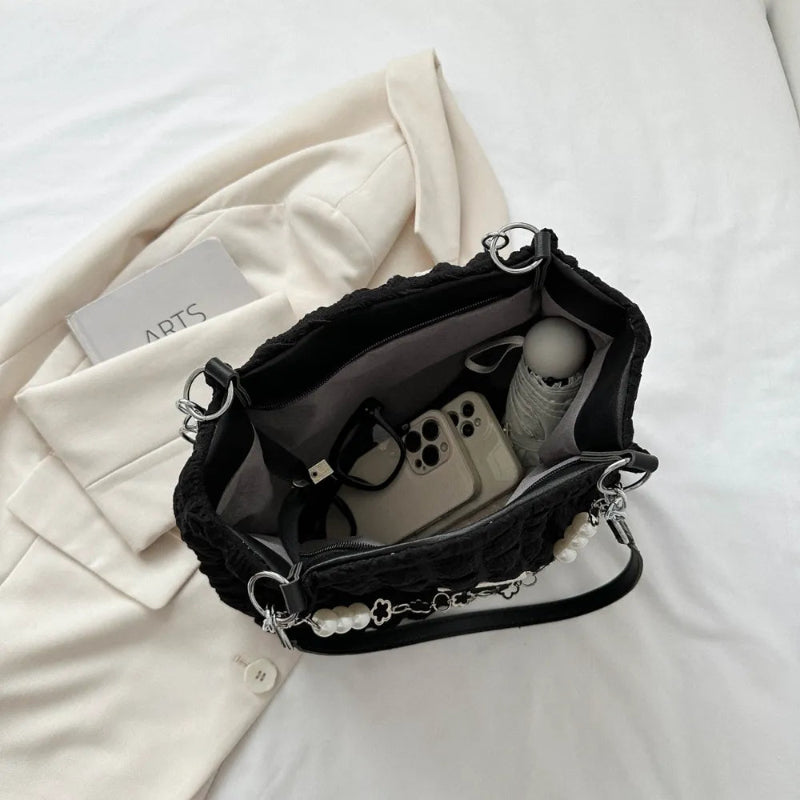 A close-up shot of a black bubble-textured tote bag with a chain detail, showcasing its unique surface and practical design.