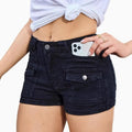 Model wearing high-waisted khaki denim shorts in street style setting, casual look with sleeveless top.