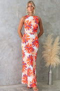 Woman modeling a one-shoulder printed sleeveless backless midi dress in lake blue, standing at sunset