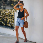 A pair of blue, high-waisted fringed denim shorts with distressed details. The shorts are laid flat on a neutral background, showcasing the style and texture. The fringe detailing is prominent along the hemline.