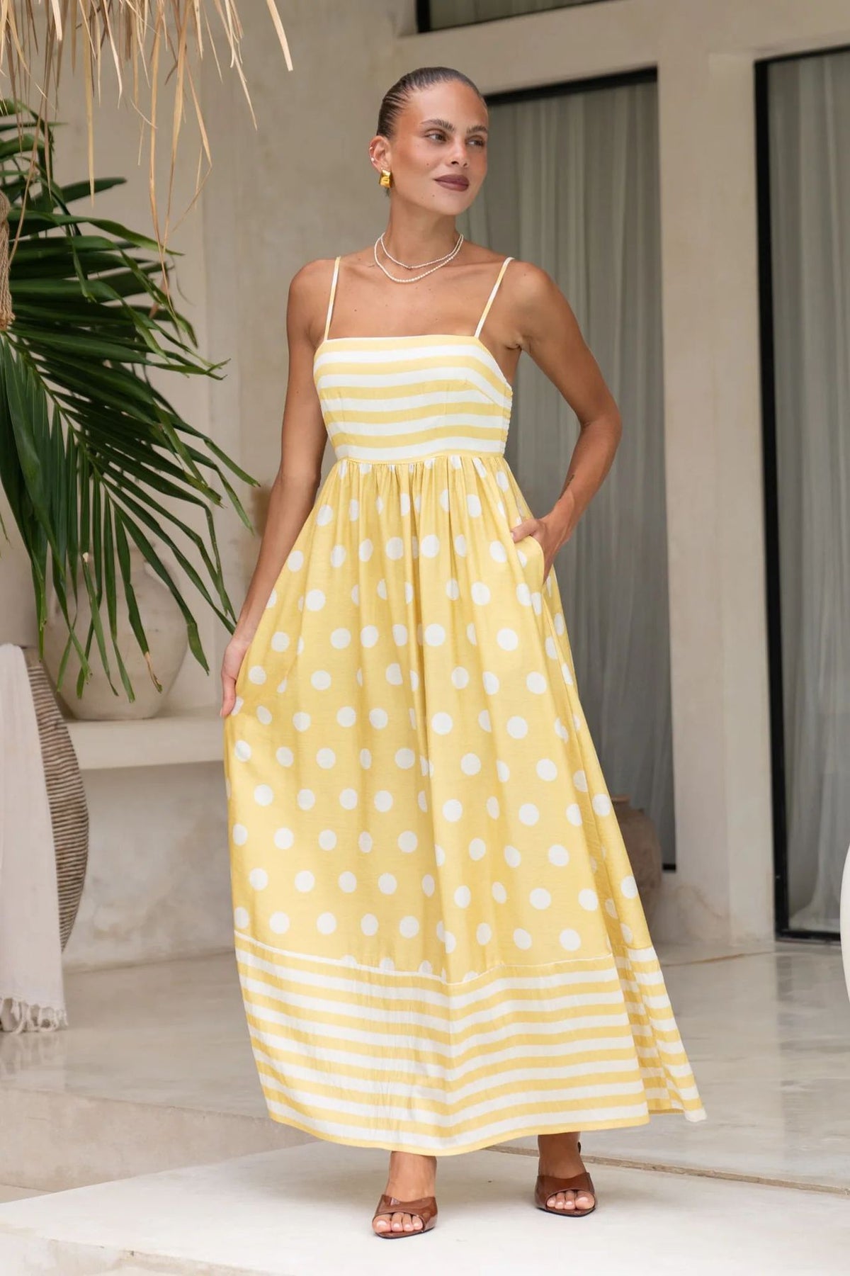 A sleeveless, high-waisted, midi-length dress with a printed pattern and a one-shoulder, backless design, photographed on a white background.