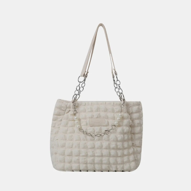A close-up shot of a black bubble-textured tote bag with a chain detail, showcasing its unique surface and practical design.