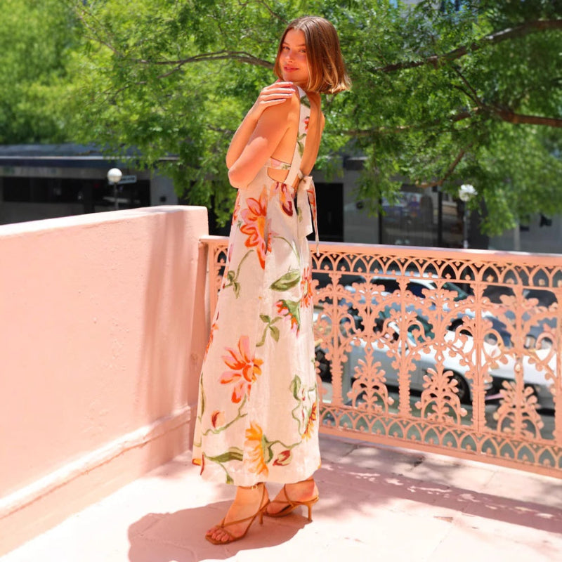 A model wearing a floral patterned, long, backless, and strapless midi dress, suitable for office wear.