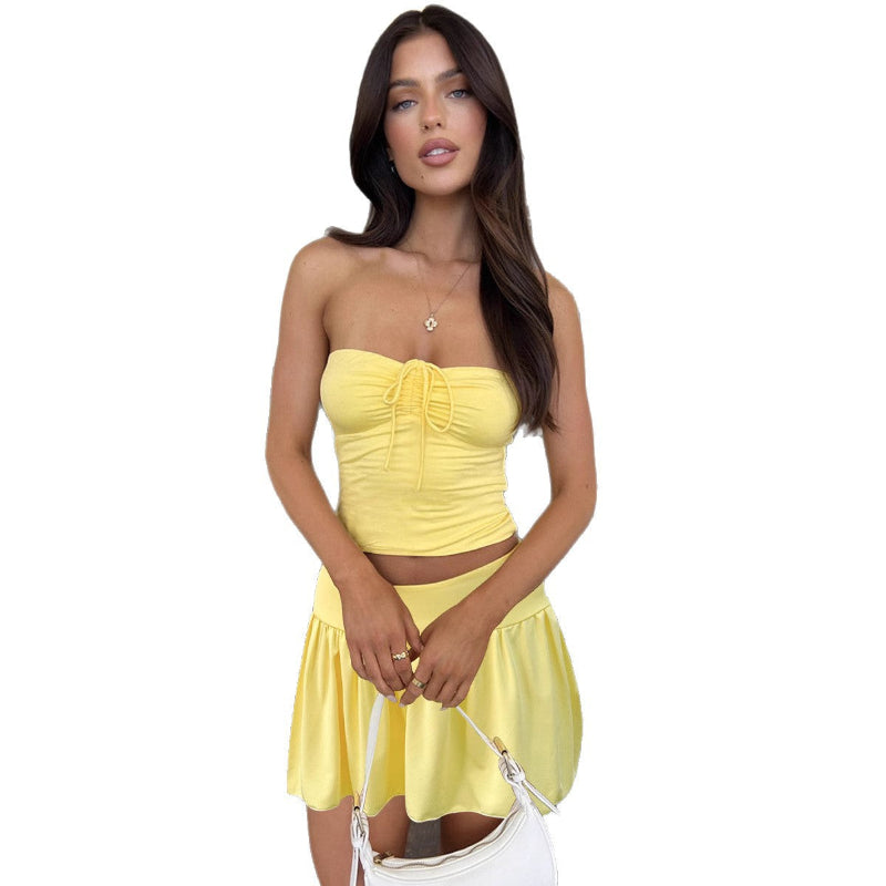 A light yellow off-shoulder tube top and a matching pleated short skirt set, displayed on a model or flat lay, showcasing a slim fit and elegant style.