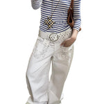 A pair of white, retro-style curved knife jeans with reverse embroidered detailing. The unique seam and leg shape are visible, highlighting the modern and edgy design.