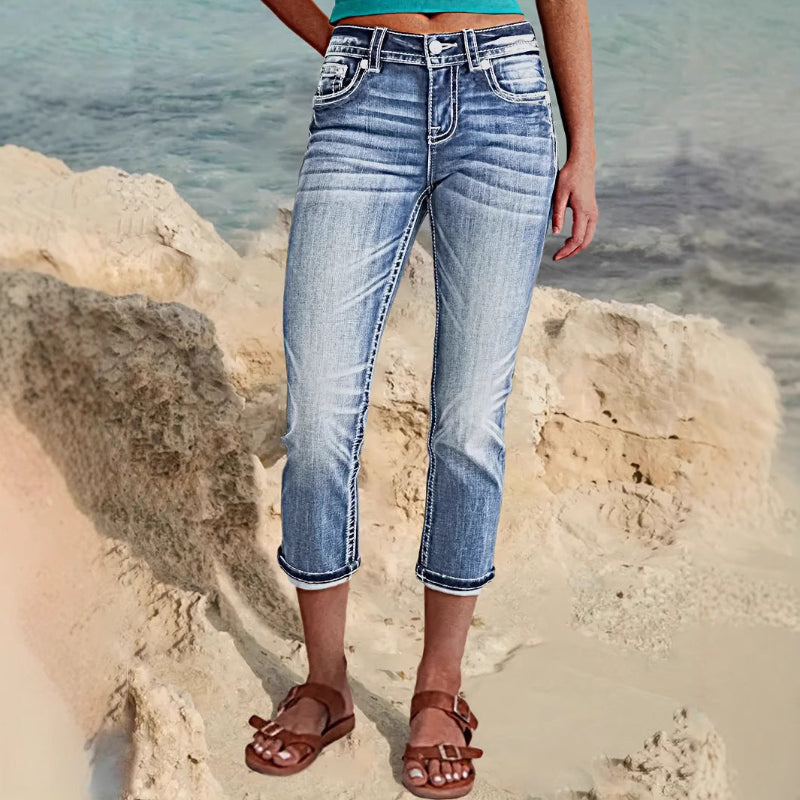 Woman wearing sky blue denim capri jeans with a flattering mid-rise fit and pocket details, standing confidently outdoors.