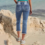 Woman wearing sky blue denim capri jeans with a flattering mid-rise fit and pocket details, standing confidently outdoors.