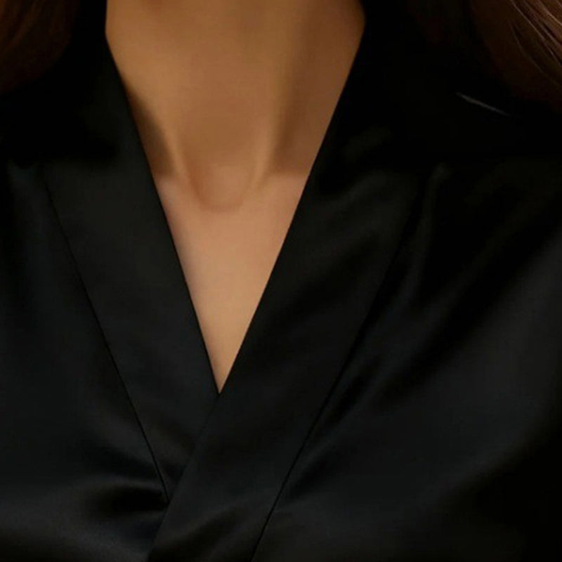 Close-up of a person wearing a black blouse with a deep neckline.