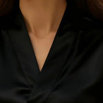 Close-up of a person wearing a black blouse with a deep neckline.