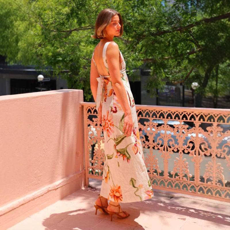 A model wearing a floral patterned, long, backless, and strapless midi dress, suitable for office wear.