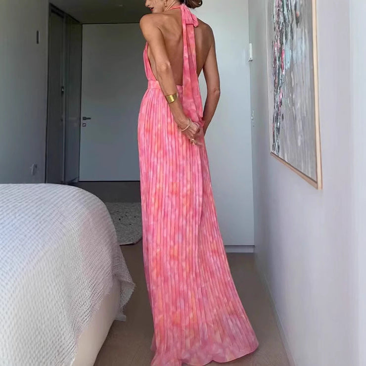 A woman from behind wearing a pink, backless, sleeveless midi dress with V-lace detailing on the back.