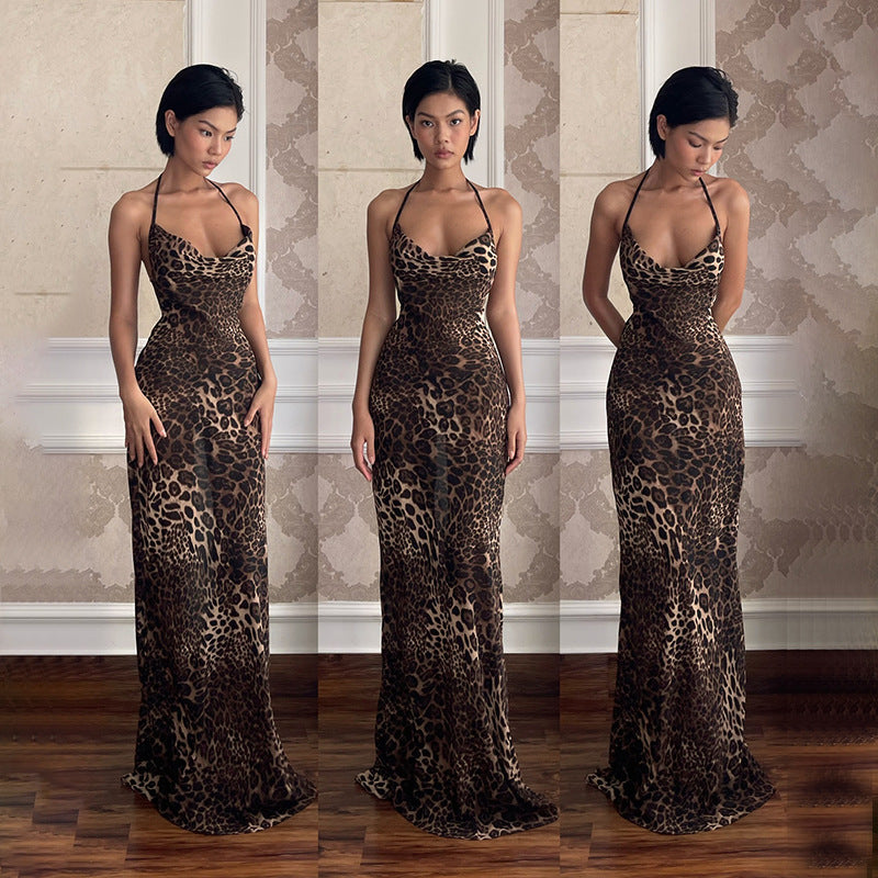 A woman confidently posing in a long, sleeveless maxi dress with a bold leopard print. The dress features a dramatic backless design and flows elegantly to the ground.