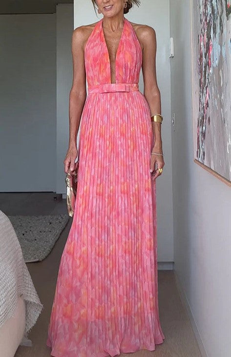 A woman from behind wearing a pink, backless, sleeveless midi dress with V-lace detailing on the back.