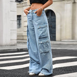 A pair of light blue, wide-leg, high-waist jeans with multiple pockets and pleated details. The jeans are displayed flat, showing the loose, straight-leg cut and zipper style.
