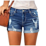 A model wearing deep blue, high-waisted denim shorts with a cuffed hem, paired with a white t-shirt. The frayed edges of the shorts are visible, and the overall style is casual and chic.