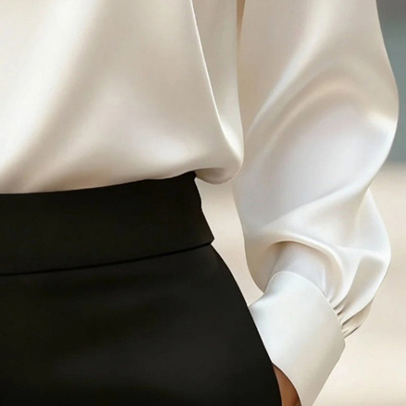 Close-up of a white blouse with a black skirt against a neutral background