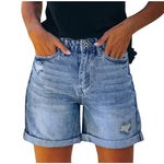 A pair of blue, high-waisted fringed denim shorts with distressed details. The shorts are laid flat on a neutral background, showcasing the style and texture. The fringe detailing is prominent along the hemline.