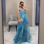 Woman wearing a strapless maxi dress with vibrant abstract print, holding gold clutch