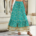 A high-waisted midi skirt with a bold digital print and a daring side slit, shown in a dark blue color. The skirt has snap buttons and is styled with a simple top.