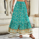 A high-waisted midi skirt with a bold digital print and a daring side slit, shown in a dark blue color. The skirt has snap buttons and is styled with a simple top.