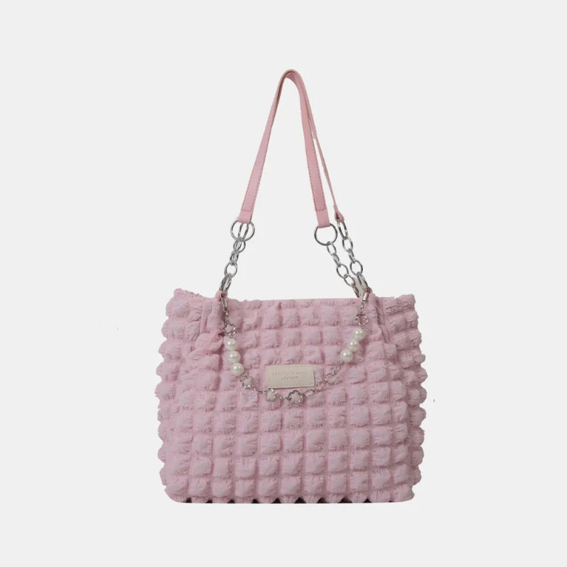 A close-up shot of a black bubble-textured tote bag with a chain detail, showcasing its unique surface and practical design.