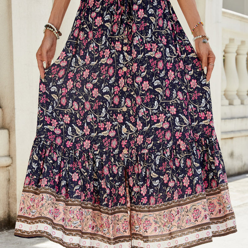A high-waisted midi skirt with a bold digital print and a daring side slit, shown in a dark blue color. The skirt has snap buttons and is styled with a simple top.