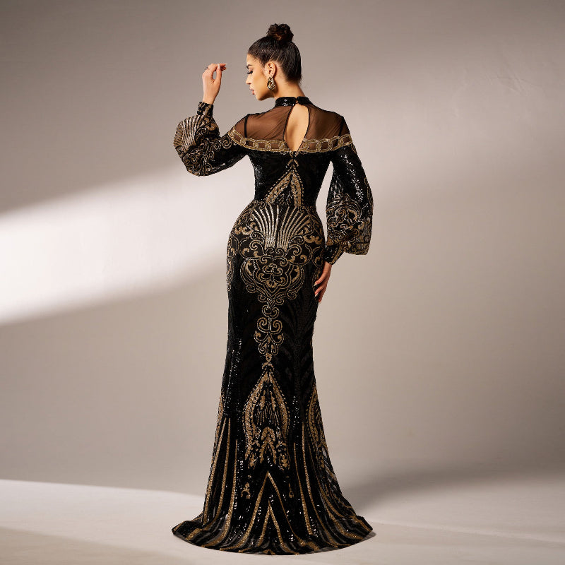 Woman wearing a black evening gown with gold embroidery against a neutral background