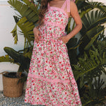 Woman in a pink floral dress standing in front of green plants