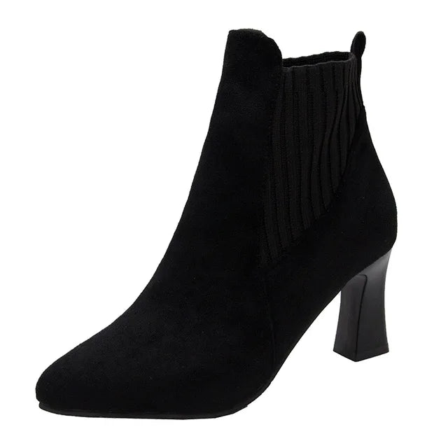 A pair of black high heel platform Martin boots with a pointed toe and thick heel.