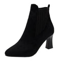 A pair of black high heel platform Martin boots with a pointed toe and thick heel.