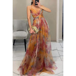Woman wearing a strapless maxi dress with vibrant abstract print, holding gold clutch