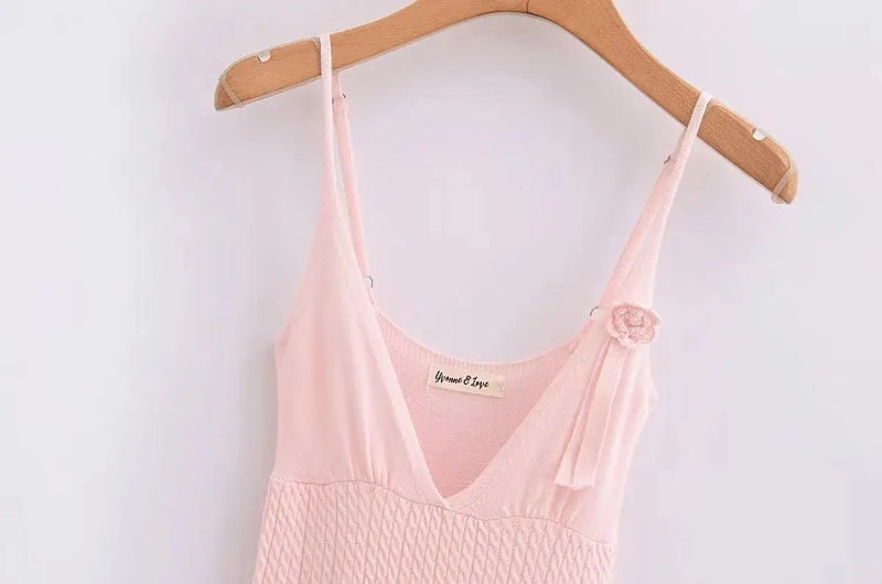 A sleeveless, V-neck, A-line mini dress in a criss-cross knitted pattern, adorned with floral appliques, available in pink and white, with a backless design.
