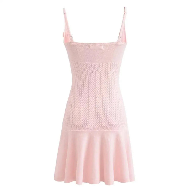 A sleeveless, V-neck, A-line mini dress in a criss-cross knitted pattern, adorned with floral appliques, available in pink and white, with a backless design.