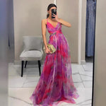 Woman wearing a strapless maxi dress with vibrant abstract print, holding gold clutch
