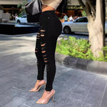 Person wearing black ripped jeans on a city street.