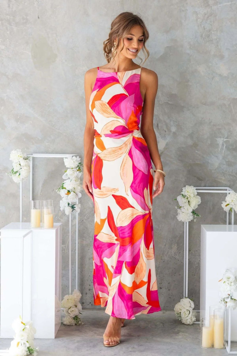 Woman modeling a one-shoulder printed sleeveless backless midi dress in lake blue, standing at sunset